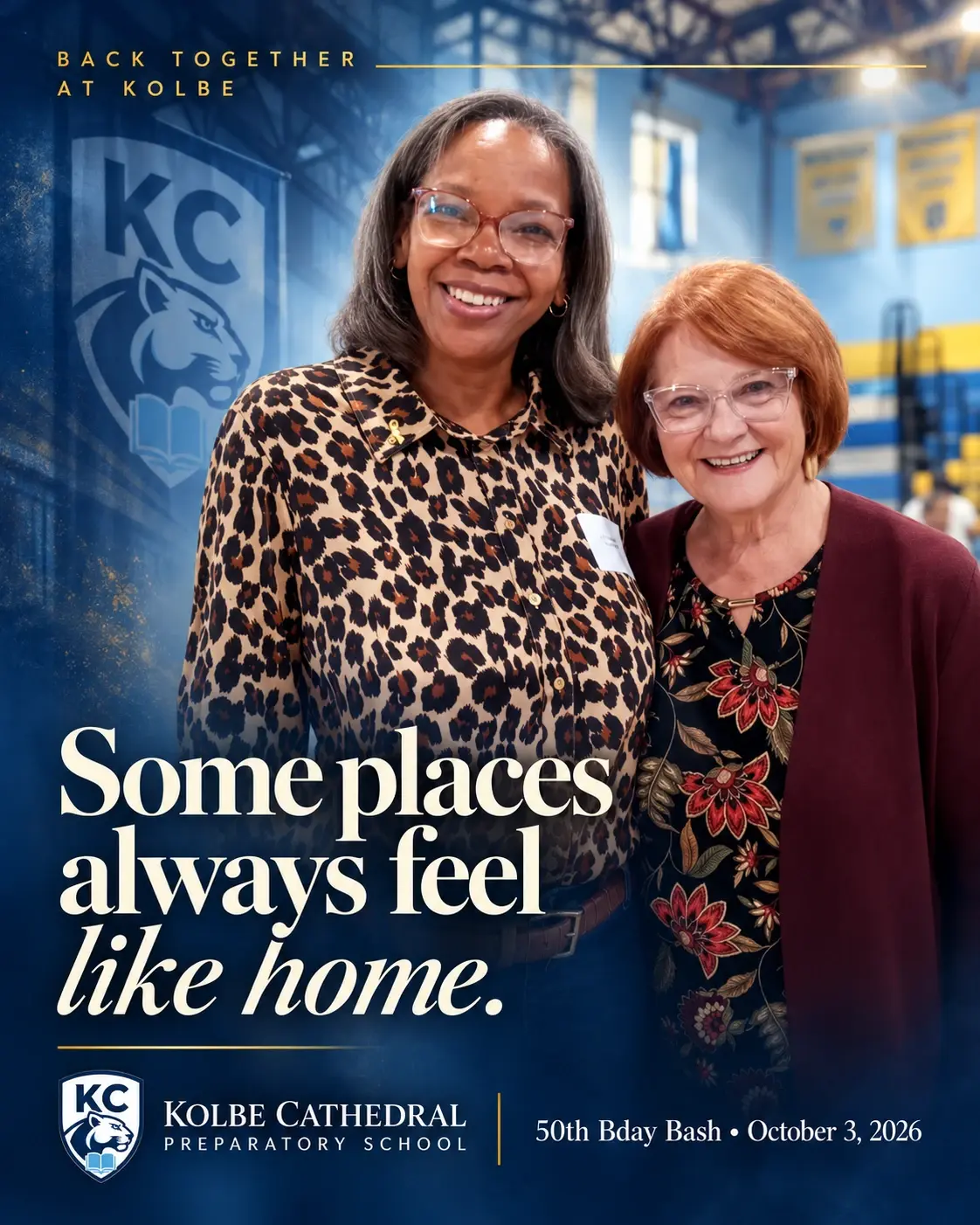 Two guests smiling together in the Kolbe gym. Back together at Kolbe: some places always feel like home. 50th Bday Bash, October 3, 2026.